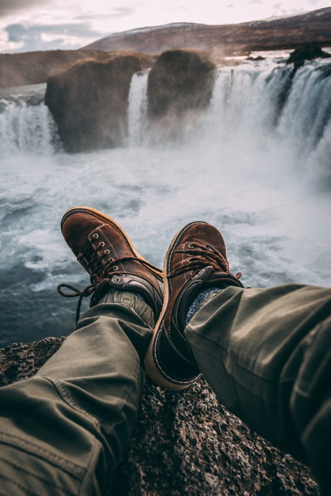 person sitting on rock near waterfalls