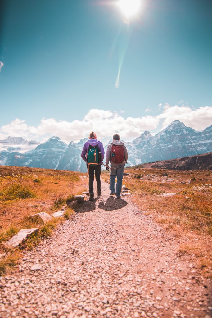 two person walking on unpaved road